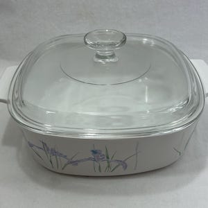 May include: Square casserole dish with a clear glass lid. The dish is white with a floral pattern of purple and blue irises. It has white handles on either side.