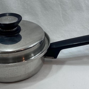 Könnte beinhalten: Edelstahl-Kochtopf mit Deckel und schwarzem Griff. Der Deckel hat einen schwarzen Knopf. Der Topf hat eine silberne Oberfläche und ist zum Kochen bestimmt. Der Griff ist lang und bietet einen bequemen Griff.
