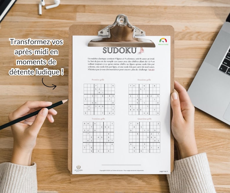 May include: A clipboard holding a Sudoku puzzle sheet with four distinct grids. The text at the top reads SUDOKU, followed by instructions in French. A black pencil is positioned to the left of the clipboard, which is placed on a wooden surface.