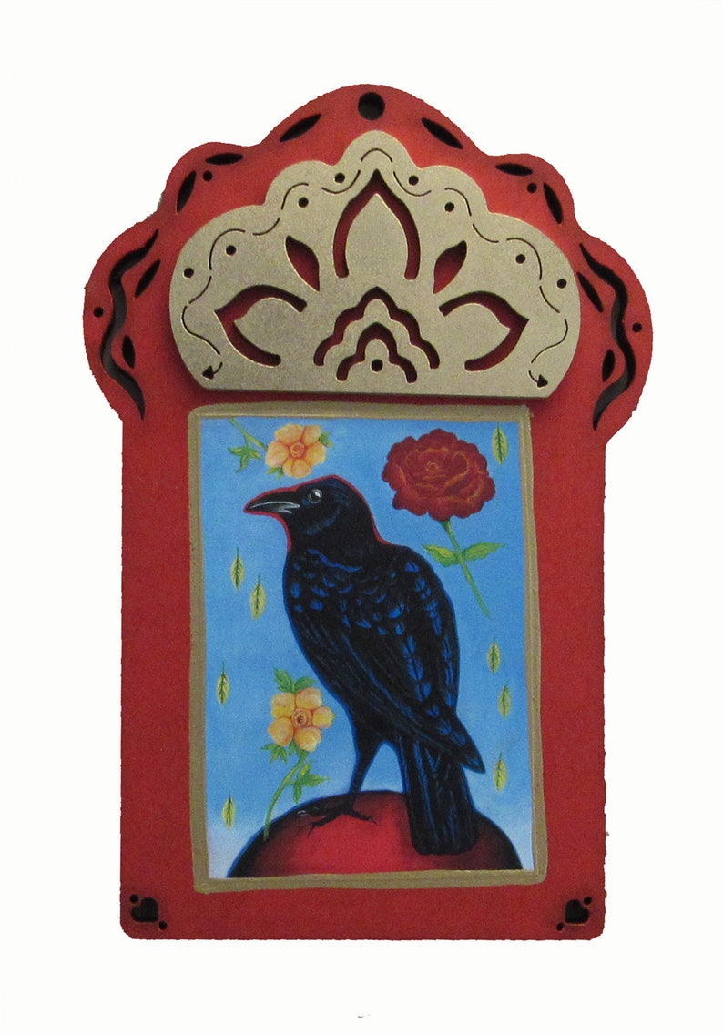 May include: A red wooden frame with a gold decorative top and a blue background. The frame contains a painting of a black crow perched on a red sphere with yellow and red flowers.
