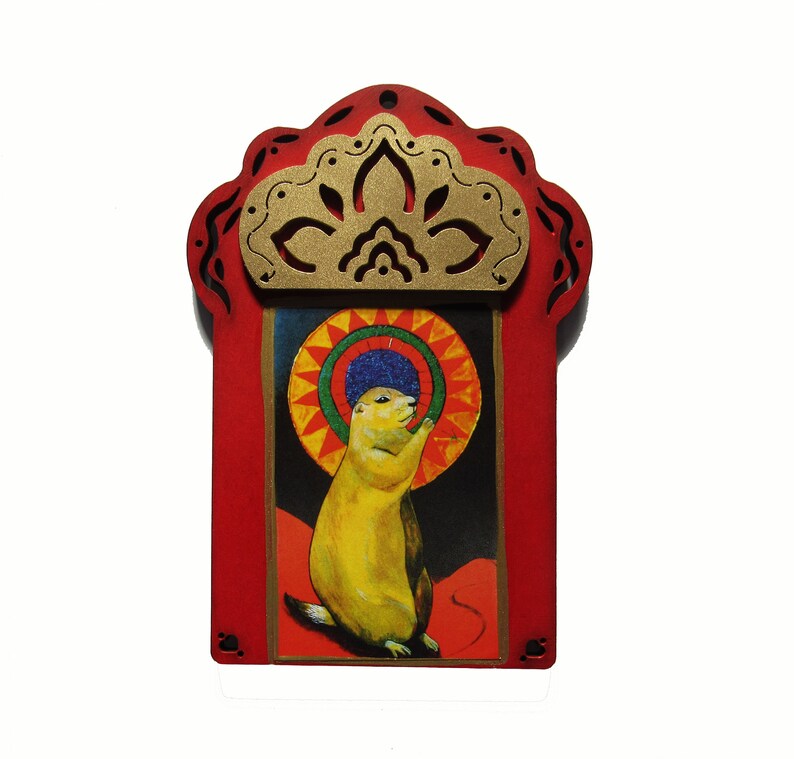 May include: A red wooden frame with a gold cutout design surrounds a colorful image of a prairie dog wearing a blue hat. The image is set against a red, yellow, and blue background.