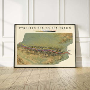 May include: A framed map titled Pyrenees Sea to Sea Trails featuring a topographic view of the mountain range between France and Spain. Three coloured lines represent hiking routes with a legend indicating GR10 800 km, HRP 800 km, and GR11 840 km.