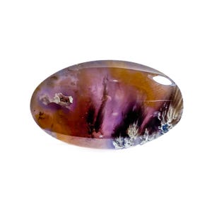 May include: An oval-shaped gemstone with a polished surface. The stone features a blend of colors, including purple, brown, and white, with a translucent quality. The gemstone has a unique pattern and texture, with a small cavity visible.
