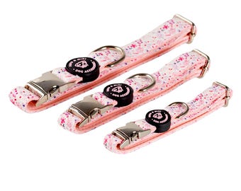 May include: Three pink dog collars with a white floral pattern and silver buckles. Each collar has a black button with the text "Mini Dog Acc" in white.