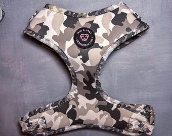 May include: A camouflage dog harness with a black and white pattern. The harness has a silver buckle and a pink logo that says "IIM & USUI DOG ACCESSORIES".