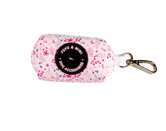 Puede incluir: Un dispensador de bolsas para recoger excrementos de perros con estampado floral rosa y blanco con un logotipo circular negro que dice "Fufu & Mini Dog Accessories".