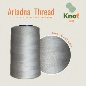 May include: A large spool of light grey Ariadna polyester thread with 5000M printed on the label. The spool is cylindrical with a dark blue top cap. A circular inset shows a close-up of the light grey thread texture labeled T007 - LIGHT GREY.
