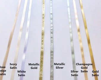 May include: A selection of satin ribbon in various colors, including ivory, white, rose beige, metallic gold, metallic silver, champagne gold, and silver. The ribbon is arranged in rows, with each color labeled below.