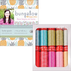 May include: A set of 10 spools of cotton thread in various shades of blue, green, pink, and red. The thread is packaged in a white box with a clear window, and the box has the text "Aurifil" printed on it. The thread is labeled "100% Cotton Thread Made in Italy".