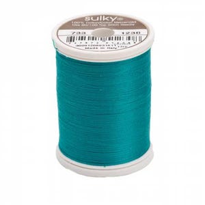 May include: A spool of teal mercerized cotton thread by Sulky. The white plastic spool features a label with the text 100% Cotton, 733, 1230, and instructions to use a 90/100 Top Stitch Needle. The thread is wound tightly around the center.