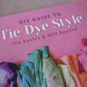 May include: A book titled "DIY Guide to Tie Dye Style: the basics & WAY beyond" with a pink cover and colorful tie-dye fabric samples.