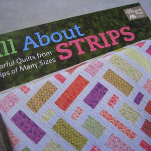 May include: A book titled "All About Strips" with a colorful quilt made from strips of fabric on the cover. The book is about making quilts from strips of fabric of many sizes.
