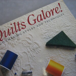 May include: A book titled "Quilts Galore! Quiltmaking Styles and Techniques" with a white cover and a red title. The cover features a green and a purple fabric sample.