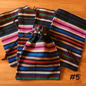 K&ouml;nnte beinhalten: F&uuml;nf Stoff-Kordelzugbeutel mit einem farbenfrohen Streifenmuster. Die Streifen umfassen Blau, Rot, Rosa und Gr&uuml;n. Jeder Beutel hat einen braunen Kordelzugverschluss. Die Nummer "#5" ist unten rechts sichtbar.