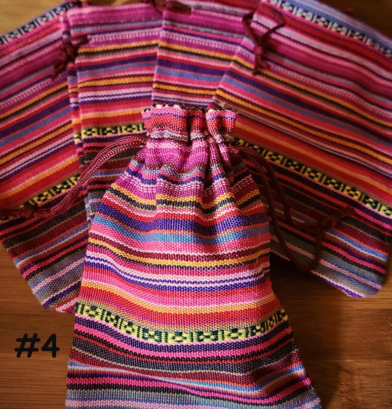 K&ouml;nnte beinhalten: Eine Sammlung farbenfroher, gestreifter Stoffbeutel mit Kordelzug und passenden Stoffst&uuml;cken. Die Beutel und der Stoff weisen ein lebhaftes Muster aus rosa, roten, blauen, gelben und gr&uuml;nen horizontalen Streifen auf. Die Nummer "#4" ist links unten in Wei&szlig; aufgedruckt.