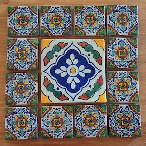 May include: A set of 13 colorful ceramic tiles with intricate geometric patterns in shades of blue, green, yellow, and red. The tiles are arranged in a grid pattern, with a larger central tile featuring a more elaborate design.