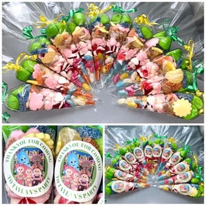 Pode incluir: Um grupo de cones de doces coloridos com laços de fita verde e amarelo. Os cones estão cheios de uma variedade de doces, incluindo jujubas, balas de goma e balas duras. Os cones são decorados com adesivos redondos que dizem "Obrigado por vir à festa do Tottaly".