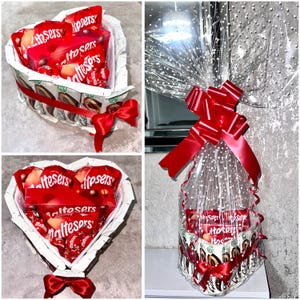 Puede incluir: Una cesta de regalo en forma de corazón llena de caramelos de chocolate Maltesers. La cesta está envuelta en celofán transparente y atada con una cinta roja. La cesta está rodeada de papel blanco y decorada con un lazo rojo.