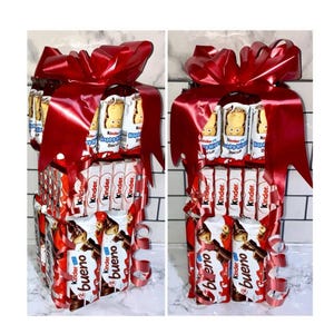 May include: A tower of chocolate bars wrapped in red ribbon. The tower is made up of Kinder chocolate bars, Kinder Bueno bars, and Kinder Happy Hippo bars.