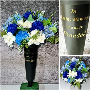 Könnte beinhalten: Eine schwarze Gedenkvase mit einem Blumenarrangement. Die Blumen sind eine Mischung aus Blau und Weiß, mit grünem Laub. Die Vase trägt den goldenen Text "In Loving Memory of a dear Grandad."