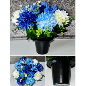 Pode incluir: Um arranjo floral artificial vibrante com flores azuis e brancas e folhas verdes. As flores são dispostas num vaso de plástico preto. Adequado para decoração de casa e adiciona cor.