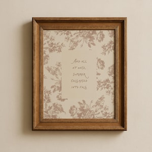 May include: A rectangular wooden picture frame with a dark brown finish containing a print. The print features a light beige background with a repeating floral pattern in a muted brown tone and the text: And all at once, summer collapsed into fall.