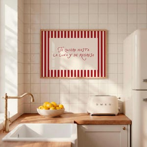 May include: A kitchen scene featuring a framed artwork with red and white stripes and the text "Te quiero hasta la luna y de regreso." A white SMEG toaster sits on a wooden countertop, along with a bowl of lemons.
