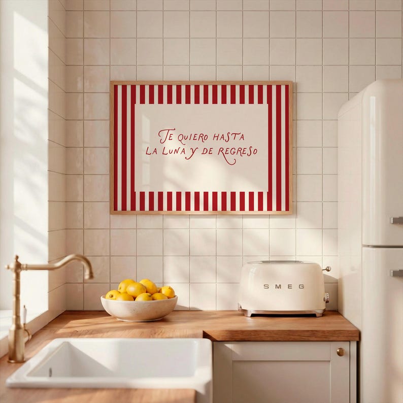 May include: A kitchen scene featuring a framed artwork with red and white stripes and the text "Te quiero hasta la luna y de regreso." A white SMEG toaster sits on a wooden countertop, along with a bowl of lemons.