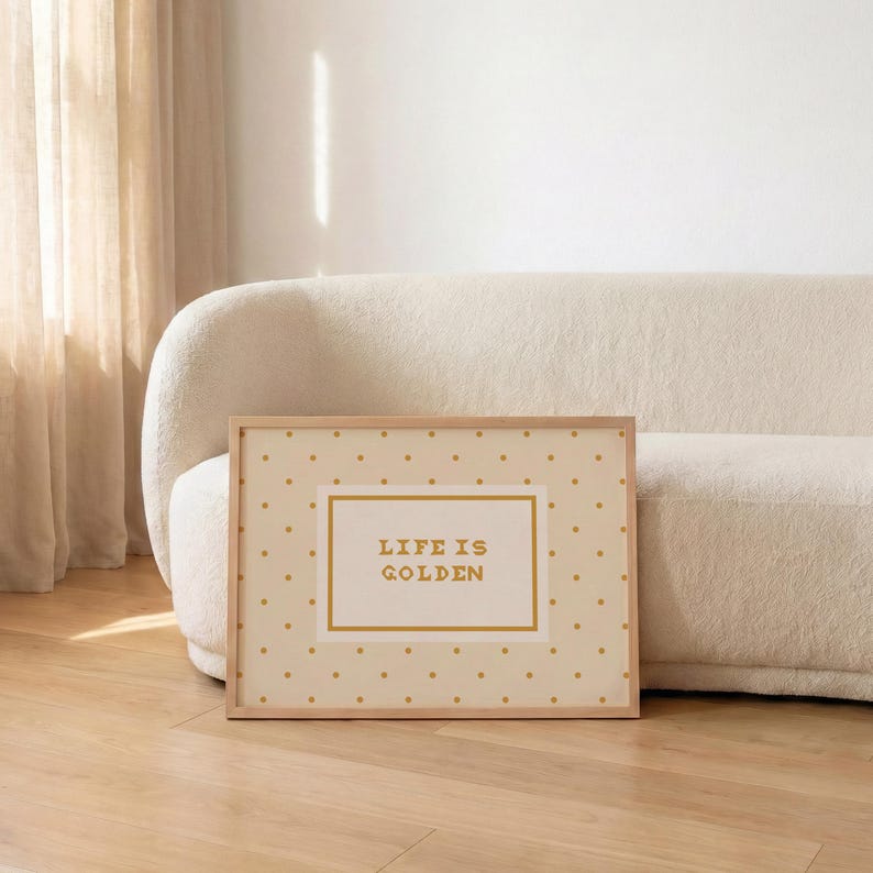Puede incluir: Una impresi&oacute;n rectangular enmarcada con un fondo crema claro y un patr&oacute;n repetitivo de peque&ntilde;os puntos dorados. En el centro, un recuadro rectangular con borde dorado contiene el texto "LIFE IS GOLDEN" impreso en una fuente dorada en negrita.
