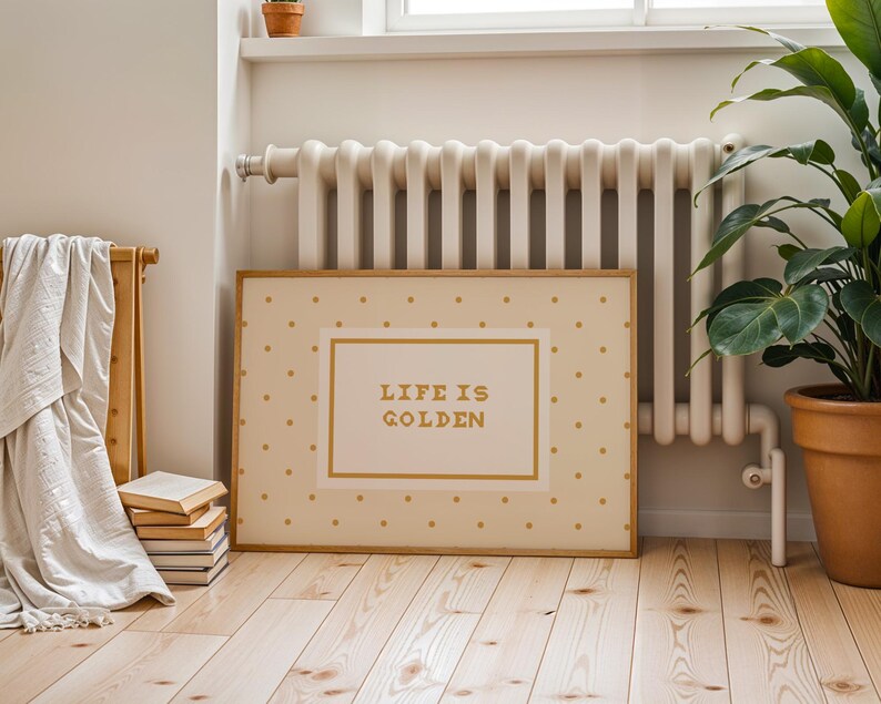 Puede incluir: Una impresi&oacute;n rectangular enmarcada con un fondo crema y un patr&oacute;n repetitivo de peque&ntilde;os puntos dorados. El centro contiene un rect&aacute;ngulo con borde dorado y el texto "LIFE IS GOLDEN" impreso en una tipograf&iacute;a dorada, negrita y sin remates.