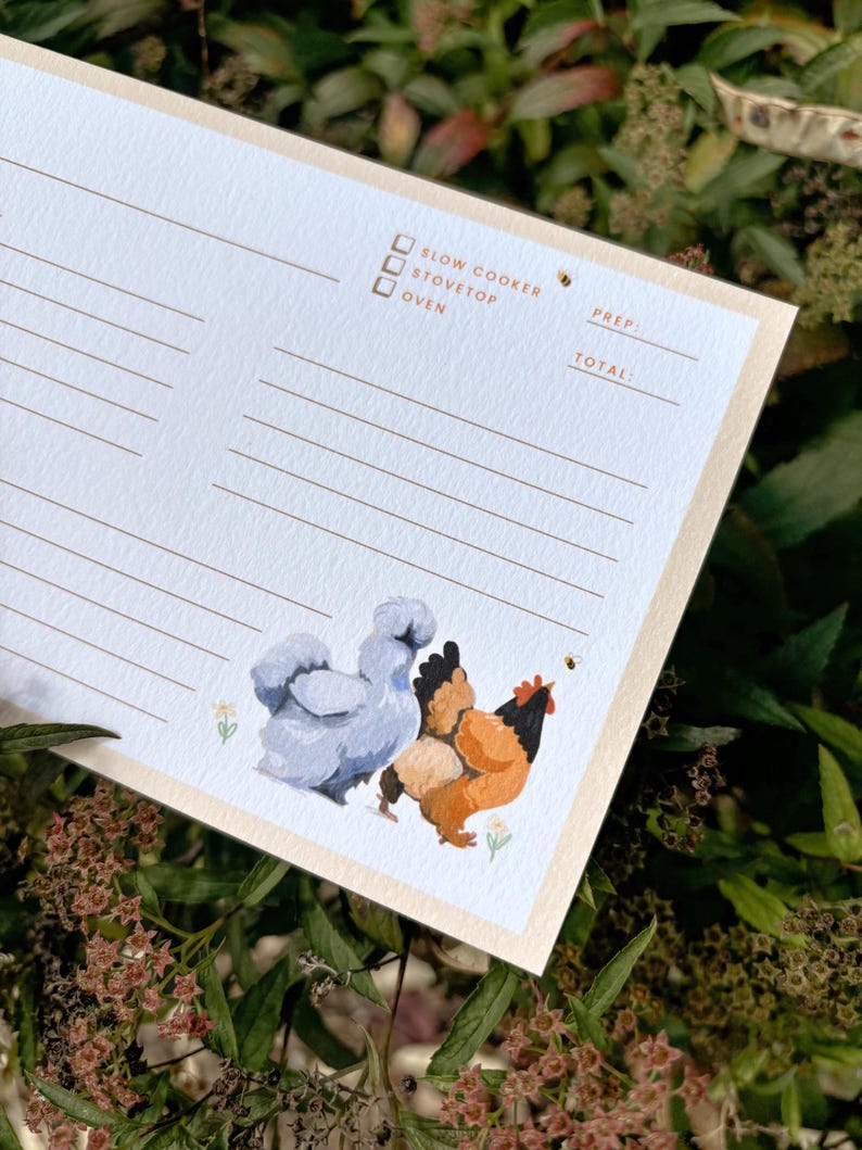 Peut inclure: Une fiche de recette avec un fond bleu clair et une bordure beige. La carte pr&eacute;sente une illustration &agrave; l'aquarelle de deux poulets et une abeille. Le texte sur la carte comprend des options pour la mijoteuse, la cuisini&egrave;re et le four.