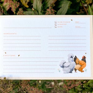 Peut inclure: Carte de recette avec un fond bleu clair et une bordure cr&egrave;me. La carte pr&eacute;sente une illustration &agrave; l'aquarelle de trois poulets. Le haut de la carte comporte des cases &agrave; cocher pour les m&eacute;thodes de cuisson. La carte est con&ccedil;ue pour &eacute;crire les ingr&eacute;dients et les instructions.