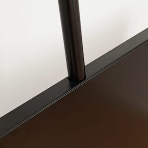 Może przedstawiać: Zbliżenie na czarną metalową ramę z czarną metalową rurką wystającą z g&oacute;ry.