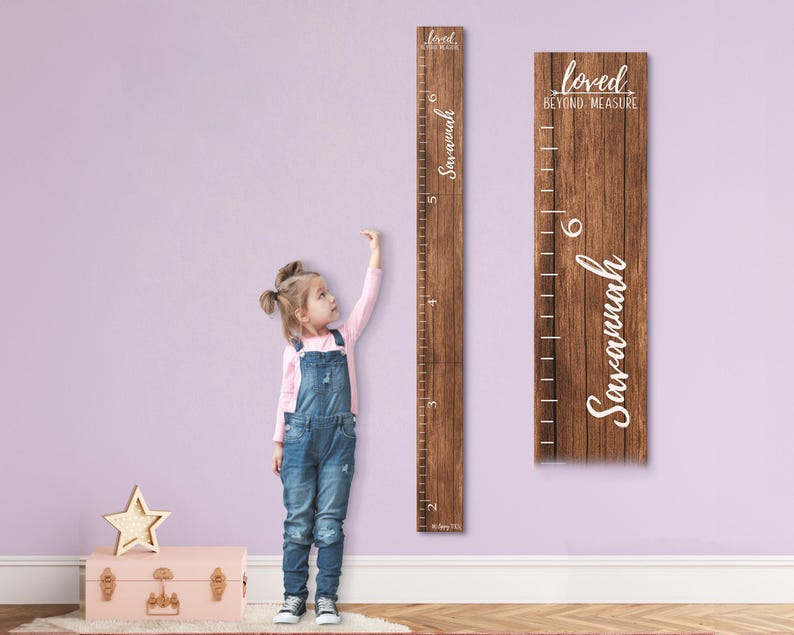 May include: A wooden growth chart with a rustic brown finish. The chart features a white inscription that reads "Loved Beyond Measure" and a personalized name "Savannah". A young girl is standing next to the chart, measuring her height.