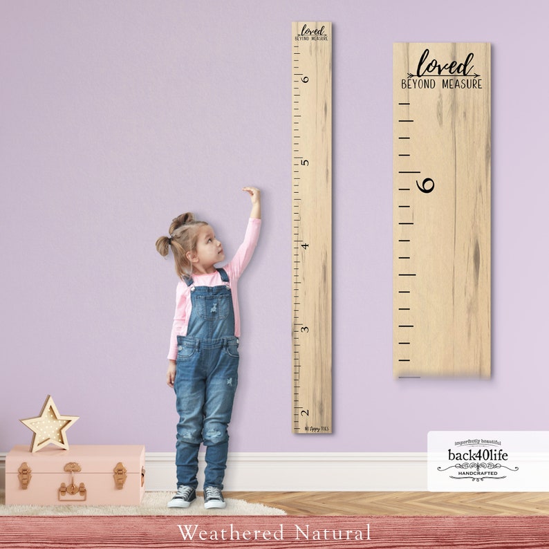 May include: A weathered natural wood growth chart with a ruler measuring up to 6 feet. The chart has the text "loved beyond measure" printed on it. A young girl is standing next to the chart, reaching up to measure her height.