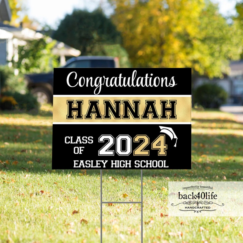 May include: Black and gold graduation yard sign with white text. The sign reads 'Congratulations Hannah Class of 2024 Easley High School'.