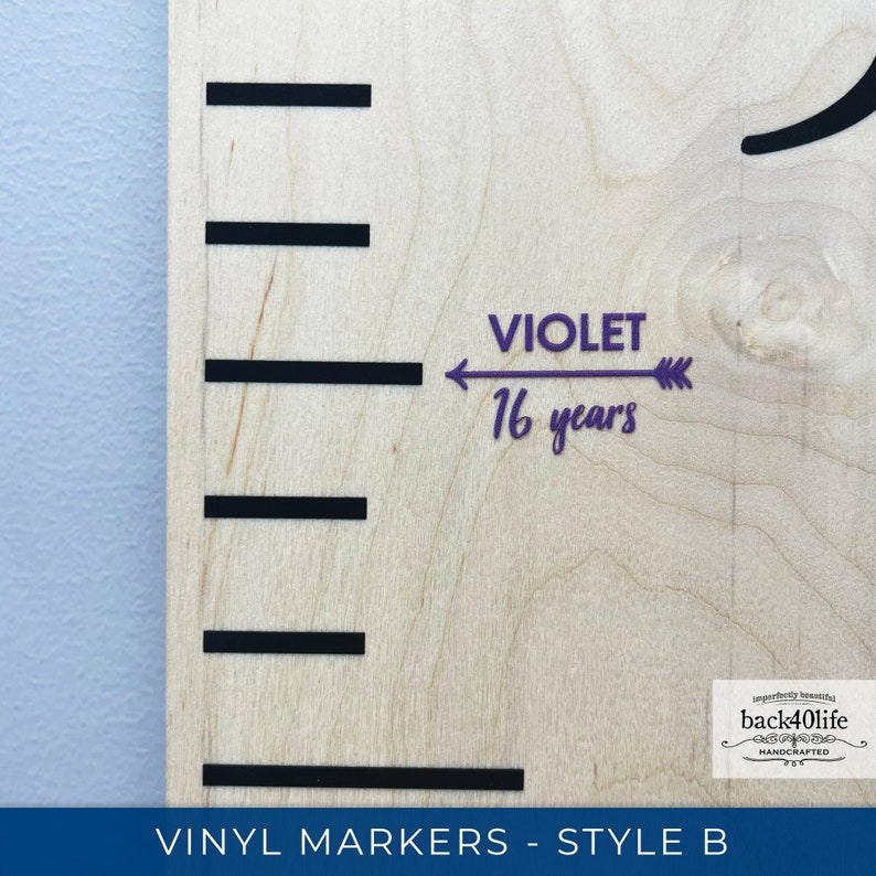 May include: A wooden growth chart with black vinyl markers and a purple vinyl arrow pointing to the text "VIOLET 16 years".