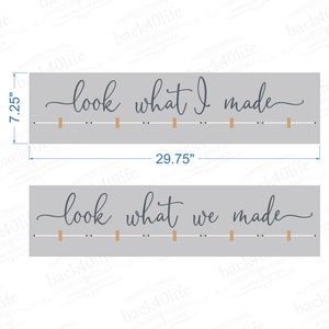 May include: Two gray wooden signs with the text "look what I made" and "look what we made" in cursive script. Each sign has a row of small wooden dowels.