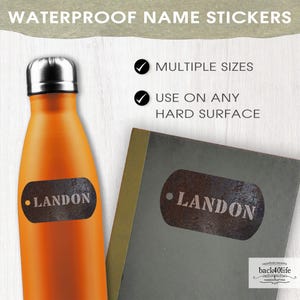 May include: Waterproof name stickers with a rustic, metal look. The stickers feature the name "LANDON" in white lettering on a brown, textured background. The stickers are shown on a water bottle and a notebook.