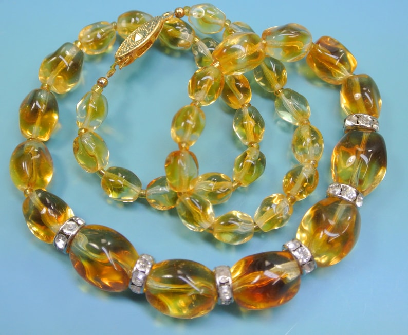 Beautiful vintage 1950s opaque goldyellow graduated oval glass bead necklace with rhinestone spacers and goldcolor metal securety clasp.