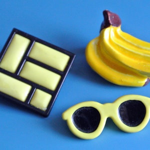 Lot of 3 vintage 1950s unused small lucite plastic yellow/ black or brown brooches with banana/sunglass/abstract motive and securety needle image 1