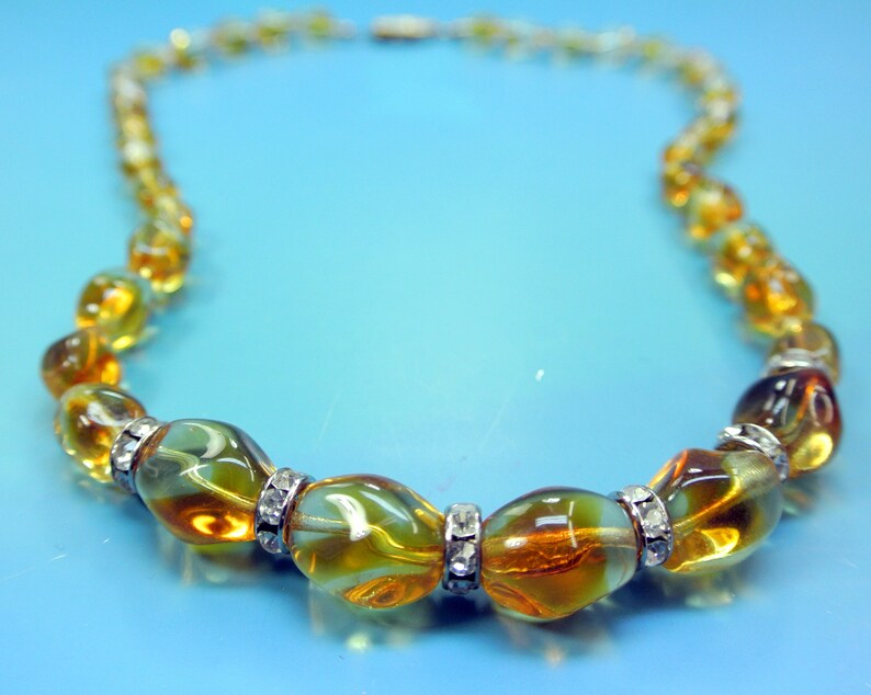 Beautiful vintage 1950s opaque goldyellow graduated oval glass bead necklace with rhinestone spacers and goldcolor metal securety clasp.