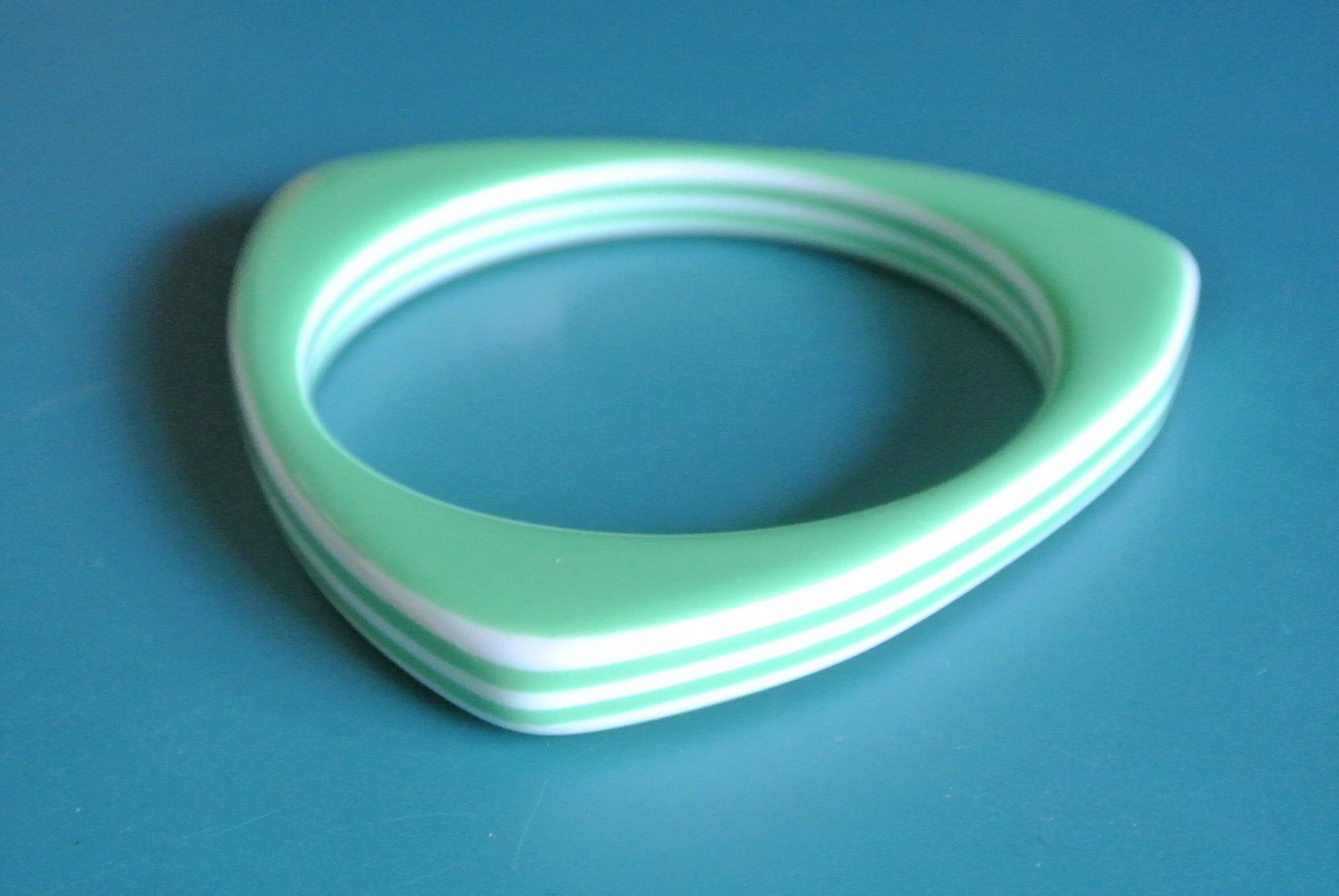 Vintage jaren 60 op-pop-tijdperk driehoekige gevormde/gelamineerde witte/lichtgroene plastic armband van lucite kunststof met gestreept decorpatroon