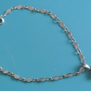 Könnte beinhalten: Ein silbernes Kettenarmband mit einem Anhänger, der mit einem Cluster aus schwarzen Edelsteinen besetzt ist.