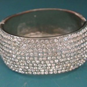 Vintage 1980s wide oval silvercolor metal feather cuff bangle bracelet with 330 faceted grinded clear stones at one side