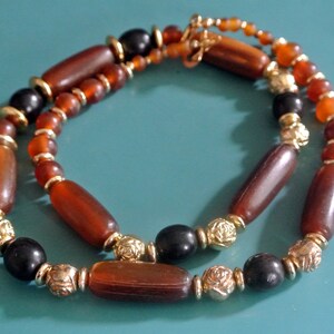 Vintage 1970s necklace of brown round/ barrel-formed plastic beads and goldcolor round rose flower beads, small spacerbeads and hook clasp