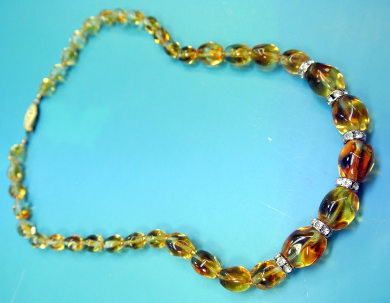 Beautiful vintage 1950s opaque goldyellow graduated oval glass bead necklace with rhinestone spacers and goldcolor metal securety clasp.