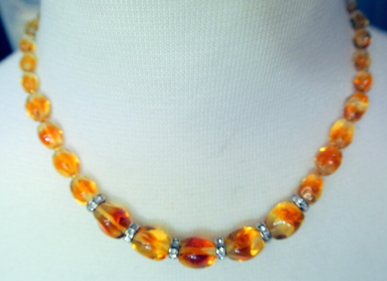 Beautiful vintage 1950s opaque goldyellow graduated oval glass bead necklace with rhinestone spacers and goldcolor metal securety clasp.