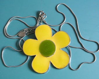 May include: A yellow flower pendant necklace with a green centre, on a silver chain.