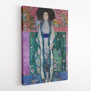 May include: A canvas print of a portrait featuring a woman in a large black hat and a long, patterned dress. The background has a floral design with pink, green, and blue hues. The artwork is mounted on a white wall.